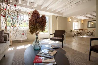 Table en bois clair avec un livre, une carte et un vase contenant une fleur verte, près d'un fauteuil blanc.