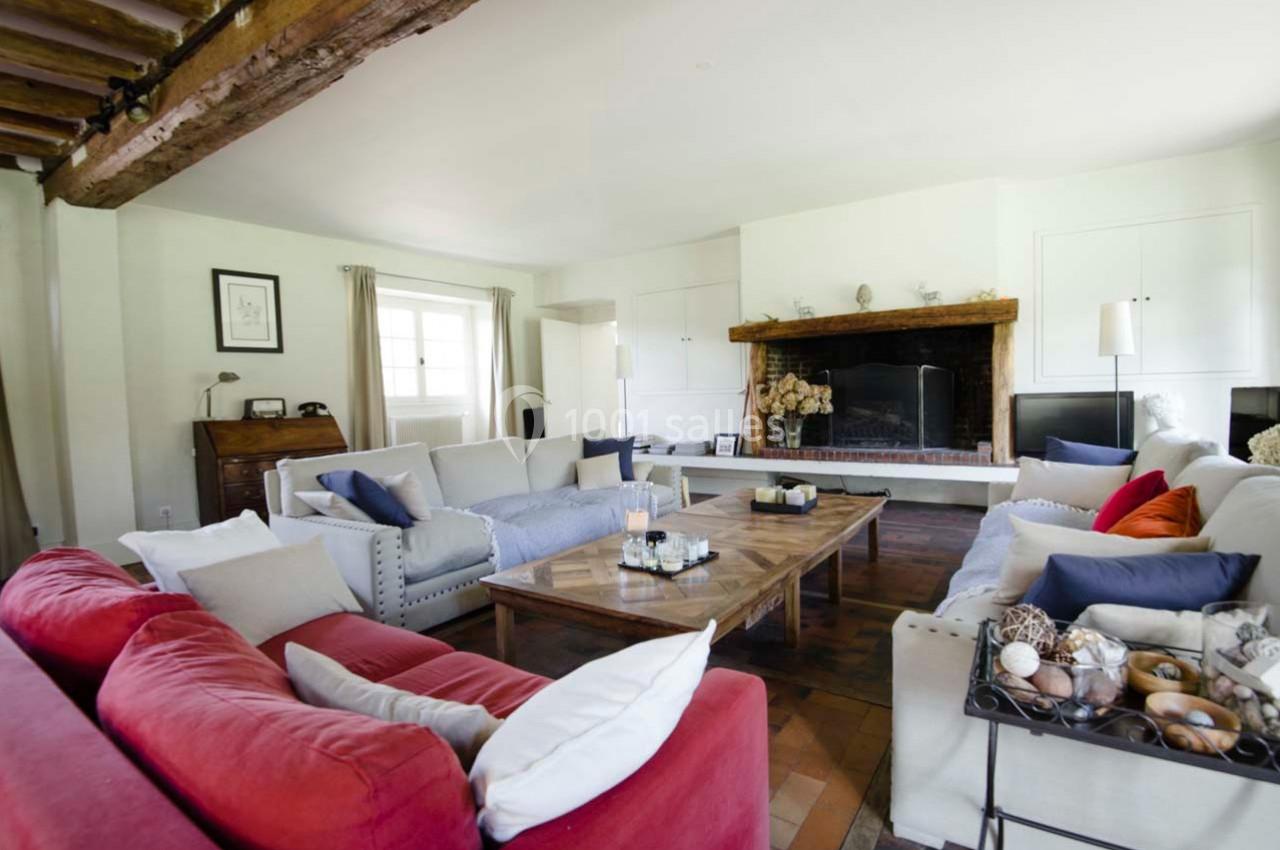 Salon lumineux avec poutres apparentes, cheminée en pierre, canapés colorés et table basse en bois massif.