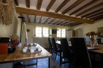 Table en bois clair avec un livre, une carte et un vase contenant une fleur verte, près d'un fauteuil blanc.