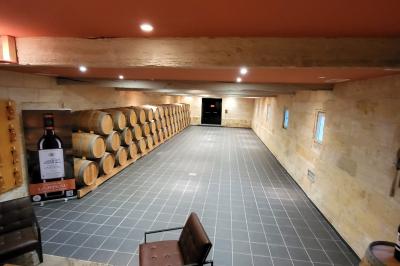 Façade d'une grande maison en pierre claire avec volets bleus, entourée d'un jardin et d'une allée gravillonnée.