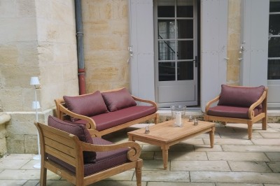 Façade d'une grande maison en pierre claire avec volets bleus, entourée d'un jardin et d'une allée gravillonnée.