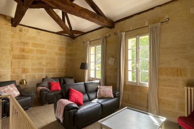 Façade d'une grande maison en pierre claire avec volets bleus, entourée d'un jardin et d'une allée gravillonnée.
