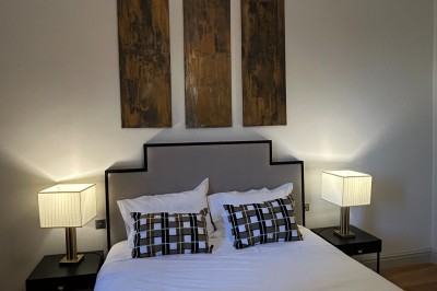 Façade d'une grande maison en pierre claire avec volets bleus, entourée d'un jardin et d'une allée gravillonnée.