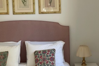 Façade d'une grande maison en pierre claire avec volets bleus, entourée d'un jardin et d'une allée gravillonnée.