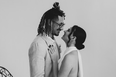 Façade d'une grande maison en pierre claire avec volets bleus, entourée d'un jardin et d'une allée gravillonnée.