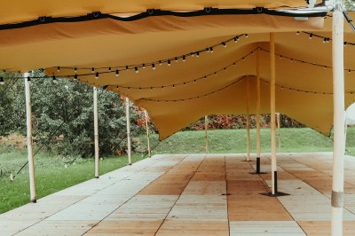 Façade d'une grande maison en pierre claire avec volets bleus, entourée d'un jardin et d'une allée gravillonnée.