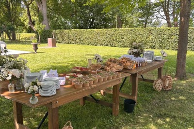 Façade d'une grande maison en pierre claire avec volets bleus, entourée d'un jardin et d'une allée gravillonnée.