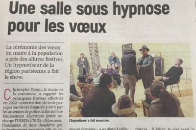 Un hypnotiseur anime une séance devant un public assis dans une salle, lors d'une cérémonie officielle.