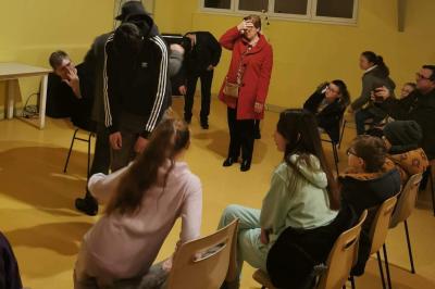 Un hypnotiseur anime une séance devant un public assis dans une salle, lors d'une cérémonie officielle.