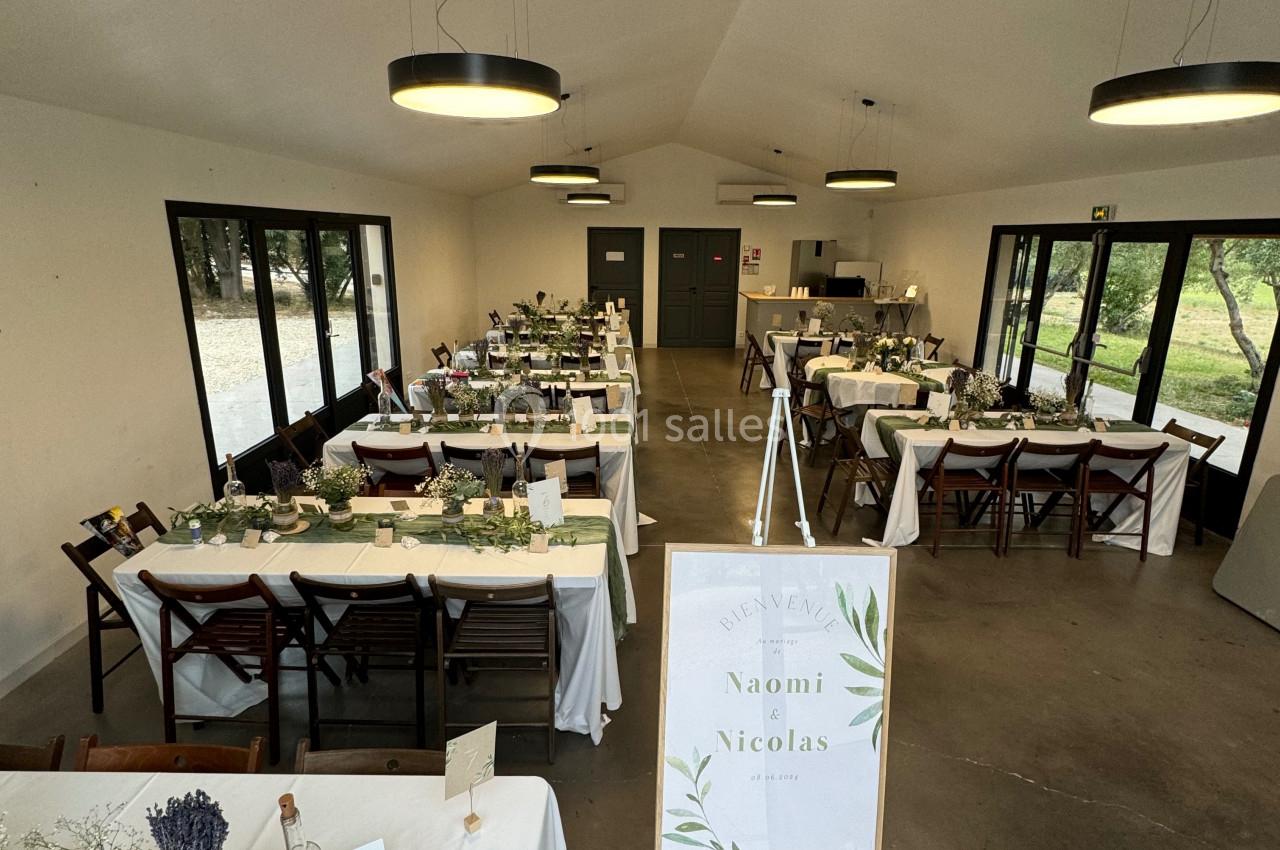 Salle de réception décorée pour un mariage, avec des tables dressées et un panneau d'accueil personnalisé.