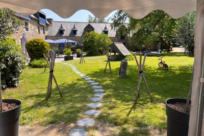 Arbuste de rhododendrons roses en fleurs dans un jardin verdoyant, sous un ciel bleu ensoleillé.