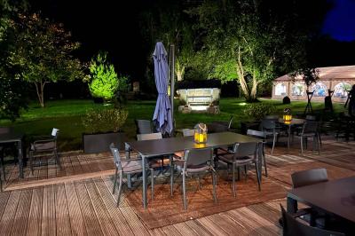 Arbuste de rhododendrons roses en fleurs dans un jardin verdoyant, sous un ciel bleu ensoleillé.