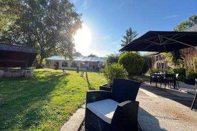 Arbuste de rhododendrons roses en fleurs dans un jardin verdoyant, sous un ciel bleu ensoleillé.