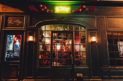 Bar à l'ambiance tamisée avec décorations colorées, tables hautes, banquettes et éclairage rouge.