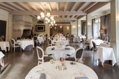 Salle de réunion lumineuse avec des tables disposées en U, des chaises noires et des fenêtres donnant sur un espace vert.