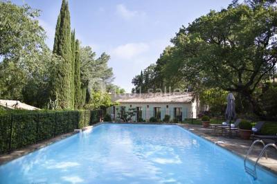 Salle de réunion lumineuse avec des tables disposées en U, des chaises noires et des fenêtres donnant sur un espace vert.