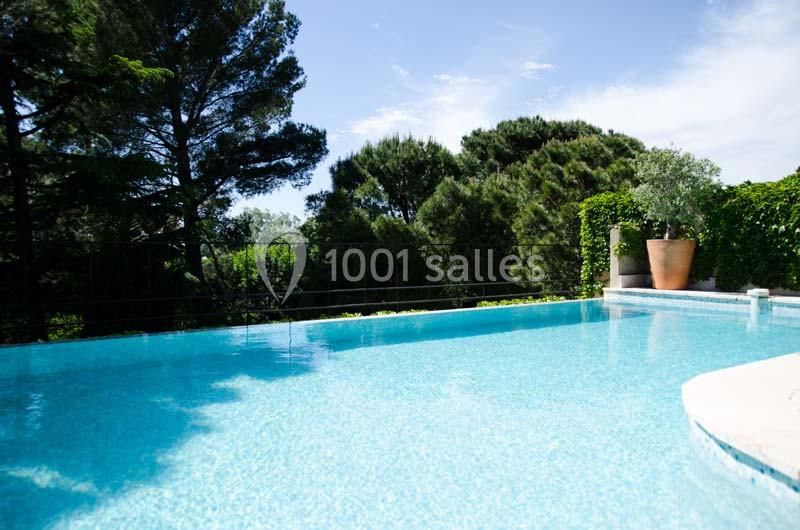 Piscine extérieure entourée de végétation dense avec ciel dégagé en arrière-plan.