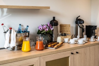Salle de réunion lumineuse avec des tables disposées en U, des chaises noires et des fenêtres donnant sur un espace vert.