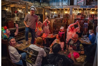 Cinq personnes souriantes posant ensemble derrière un grand cadre doré, devant un fond de rideaux rouges.