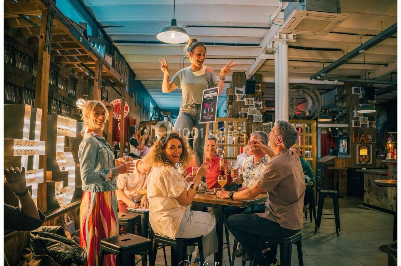 Un groupe de personnes partage un moment convivial dans un bar, avec une femme debout sur une table.