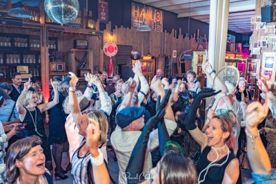 Cinq personnes souriantes posant ensemble derrière un grand cadre doré, devant un fond de rideaux rouges.