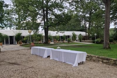 Deux tables rondes décorées pour un événement, avec nappes blanches, fleurs, verres et serviettes pliées.