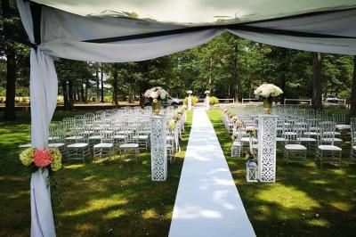 Deux tables rondes décorées pour un événement, avec nappes blanches, fleurs, verres et serviettes pliées.