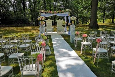 Deux tables rondes décorées pour un événement, avec nappes blanches, fleurs, verres et serviettes pliées.