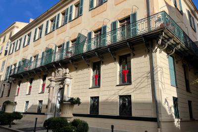 Escalier intérieur avec rampe en fer forgé, miroir mural, appliques dorées et fresque artistique sur le mur.