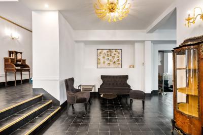 Escalier intérieur avec rampe en fer forgé, miroir mural, appliques dorées et fresque artistique sur le mur.