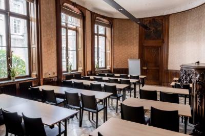 Couloir lumineux avec moquette verte, plantes en pot et portes blanches vitrées au fond.