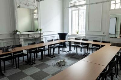 Couloir lumineux avec moquette verte, plantes en pot et portes blanches vitrées au fond.