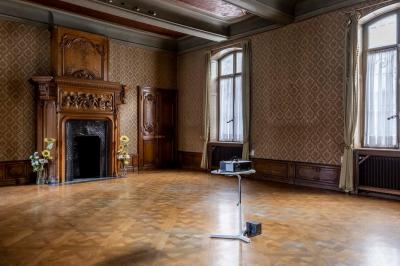 Couloir lumineux avec moquette verte, plantes en pot et portes blanches vitrées au fond.