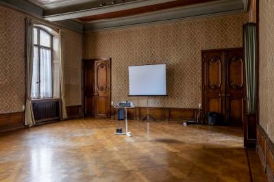 Couloir lumineux avec moquette verte, plantes en pot et portes blanches vitrées au fond.