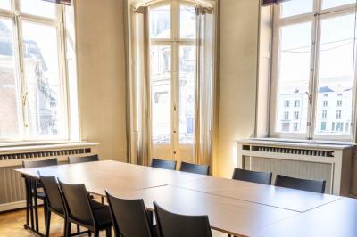 Couloir lumineux avec moquette verte, plantes en pot et portes blanches vitrées au fond.