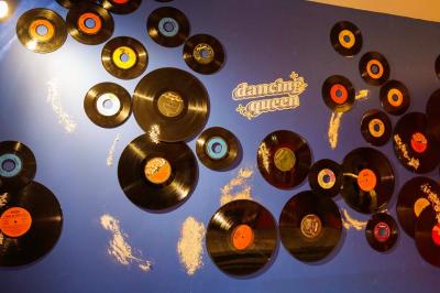 Mur décoré de vinyles, panneau des Rolling Stones et lampes modernes, avec un papier peint coloré en arrière-plan.