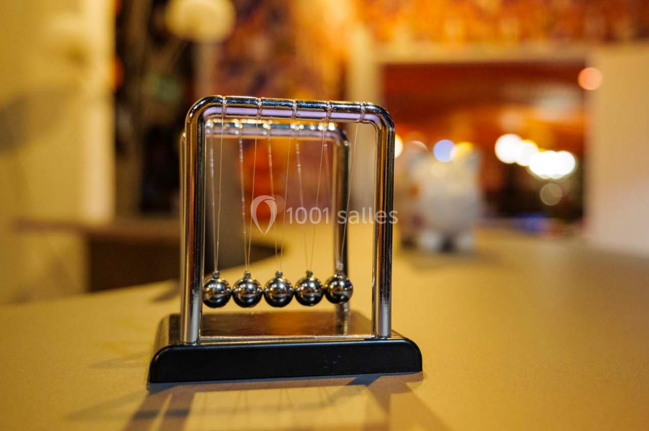 Balles d'un pendule de Newton en métal alignées sur une table, avec un arrière-plan flou et lumineux.