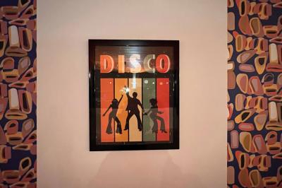 Mur décoré de vinyles, panneau des Rolling Stones et lampes modernes, avec un papier peint coloré en arrière-plan.