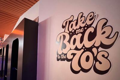 Mur décoré de vinyles, panneau des Rolling Stones et lampes modernes, avec un papier peint coloré en arrière-plan.