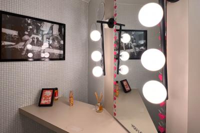 Miroir éclairé par des ampoules rondes dans une salle de bain au décor minimaliste avec cadre et accessoires.