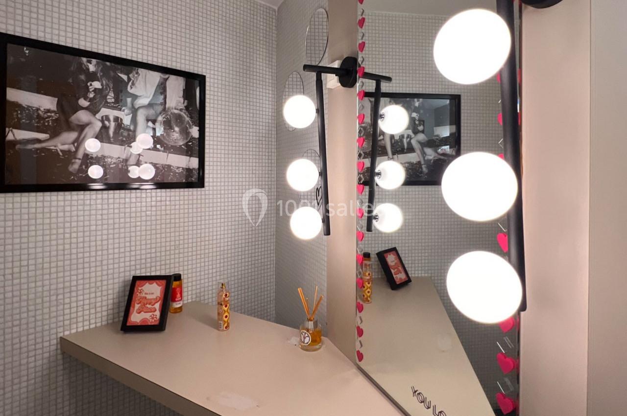 Miroir éclairé par des ampoules rondes dans une salle de bain au décor minimaliste avec cadre et accessoires.