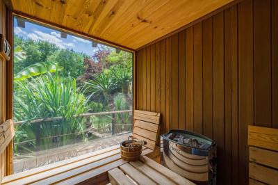 Un vase en verre avec des feuilles vertes posé sur une table dressée en extérieur, entourée de végétation.