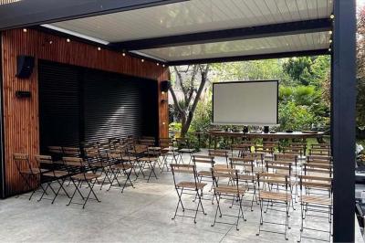 Un vase en verre avec des feuilles vertes posé sur une table dressée en extérieur, entourée de végétation.