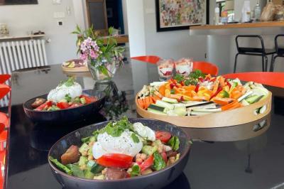 Un vase en verre avec des feuilles vertes posé sur une table dressée en extérieur, entourée de végétation.