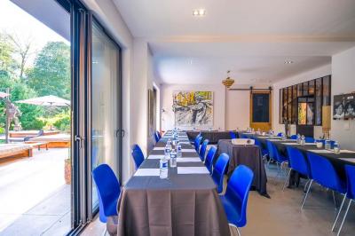 Un vase en verre avec des feuilles vertes posé sur une table dressée en extérieur, entourée de végétation.