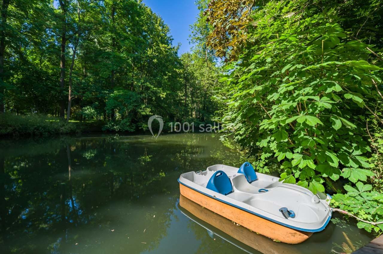 Pédalo amarré sur une rivière calme entourée de végétation dense et d'arbres verdoyants.