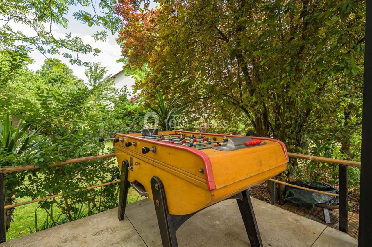 Baby-foot en bois installé sur une terrasse entourée de végétation luxuriante.