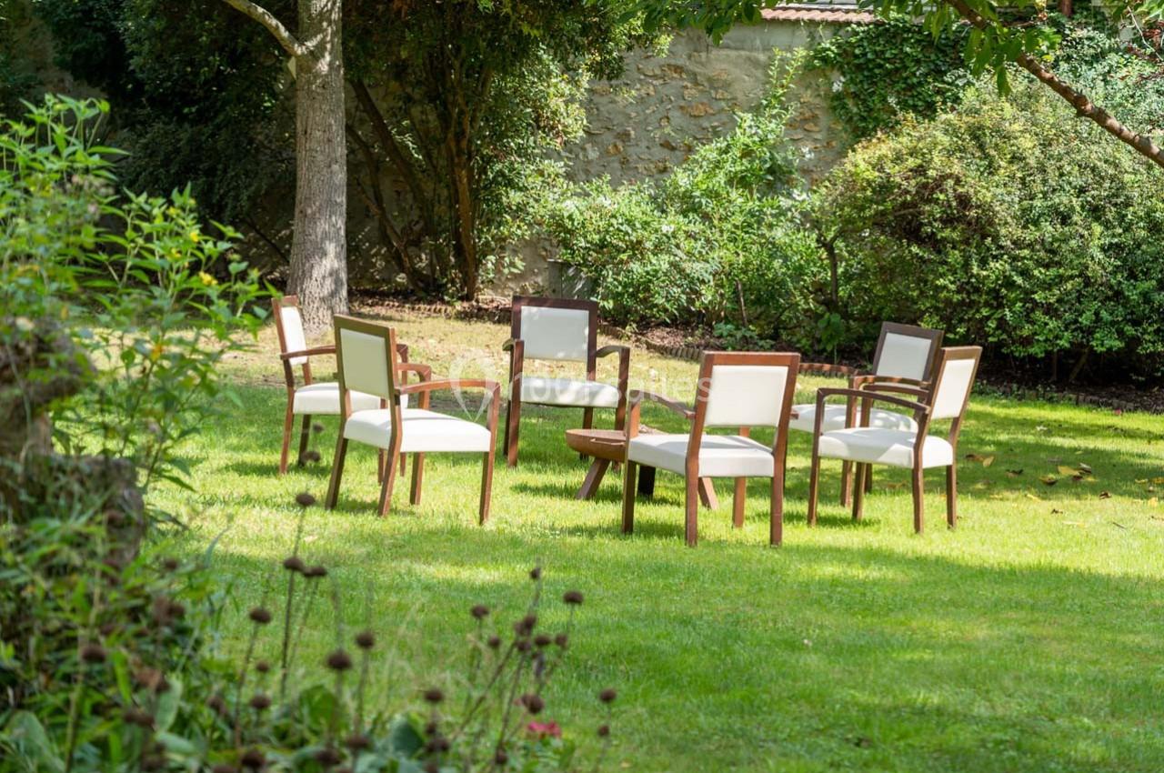 Chaises disposées en cercle sur une pelouse dans un jardin arboré.