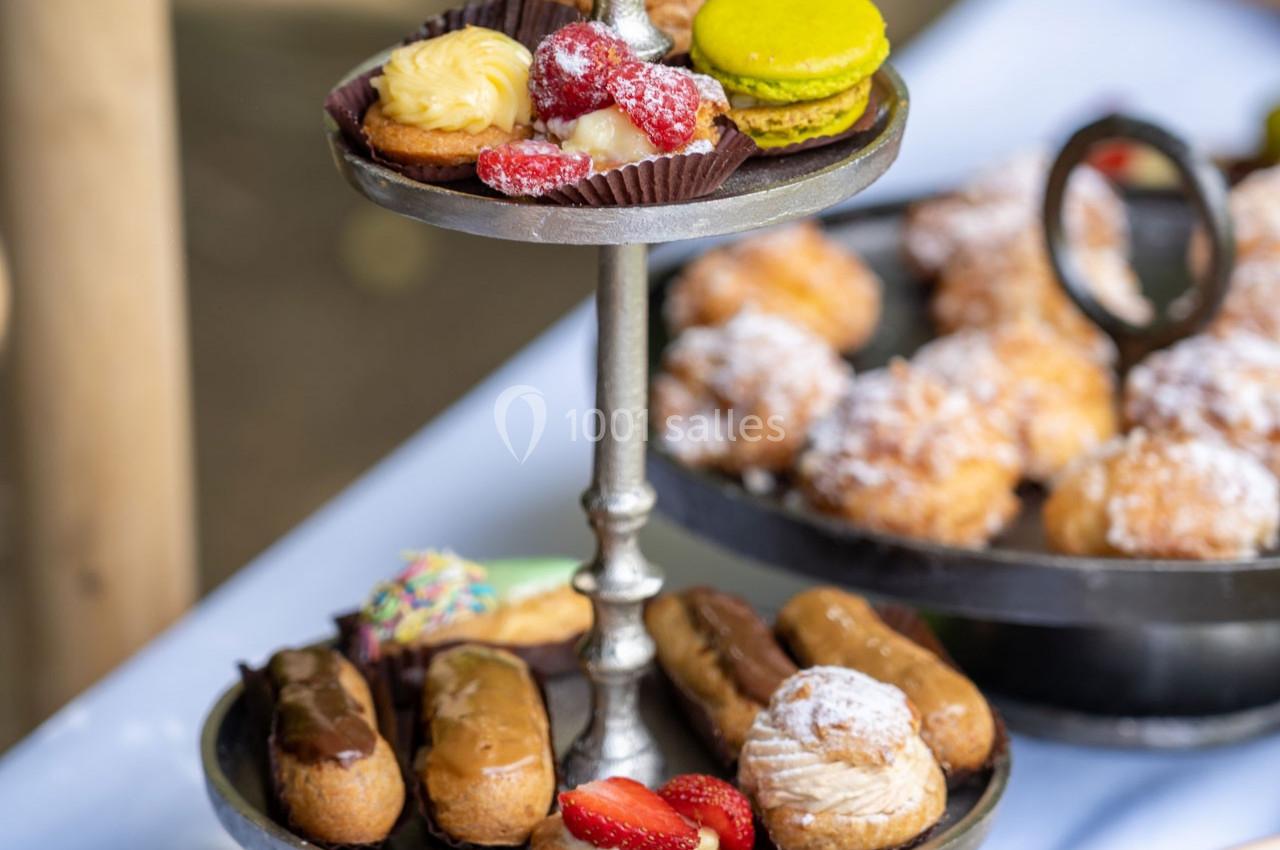 Plateau à deux étages avec éclairs, macarons, tartelettes et autres pâtisseries disposés sur une table.