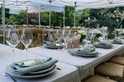 Tables dressées avec nappes blanches, vaisselle élégante, verres à pied et décorations florales sous des tonnelles…